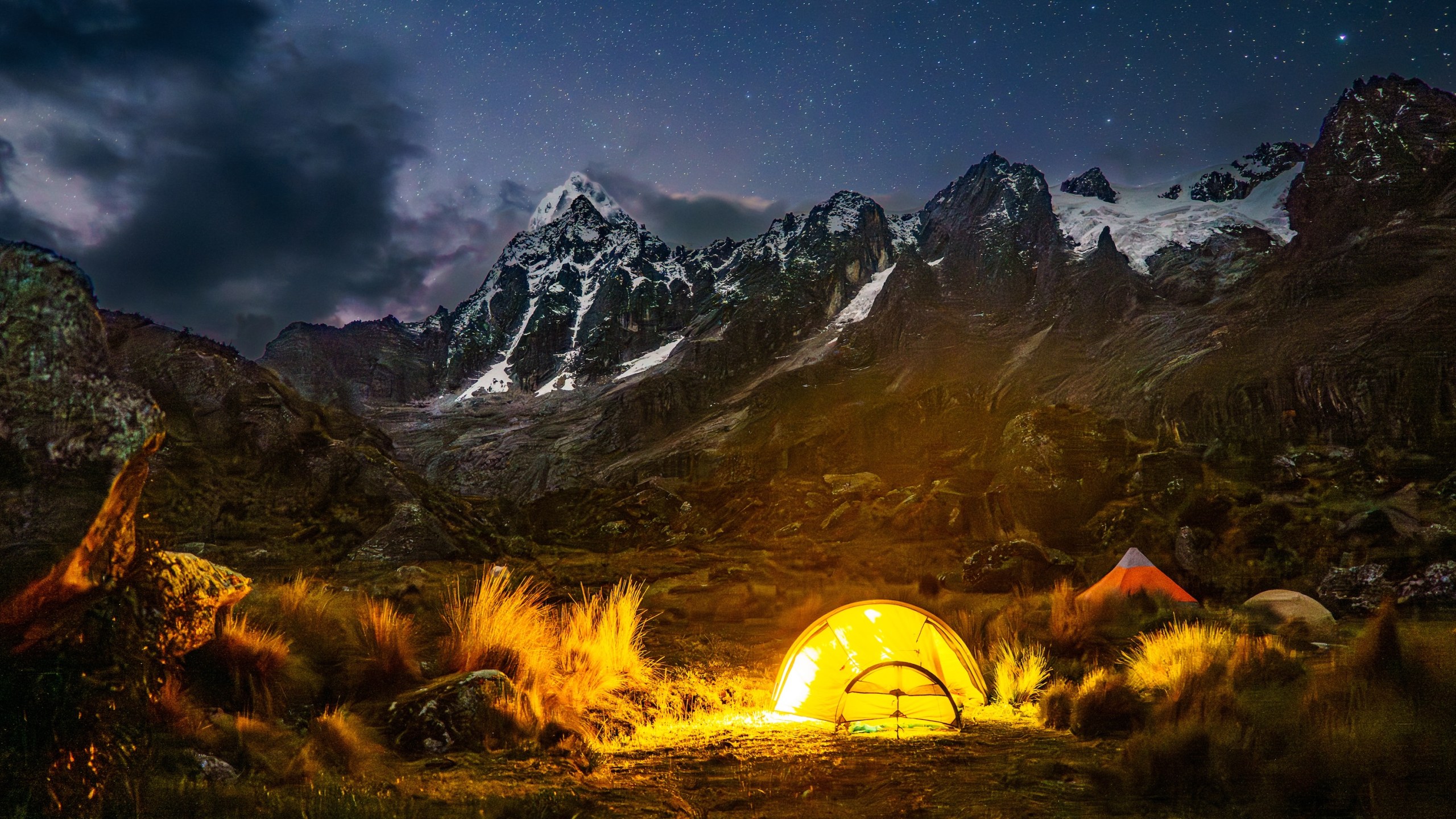 Glowing tent beneath snow-capped peaks and a starry night sky, Cordillera Blanca, Peru
