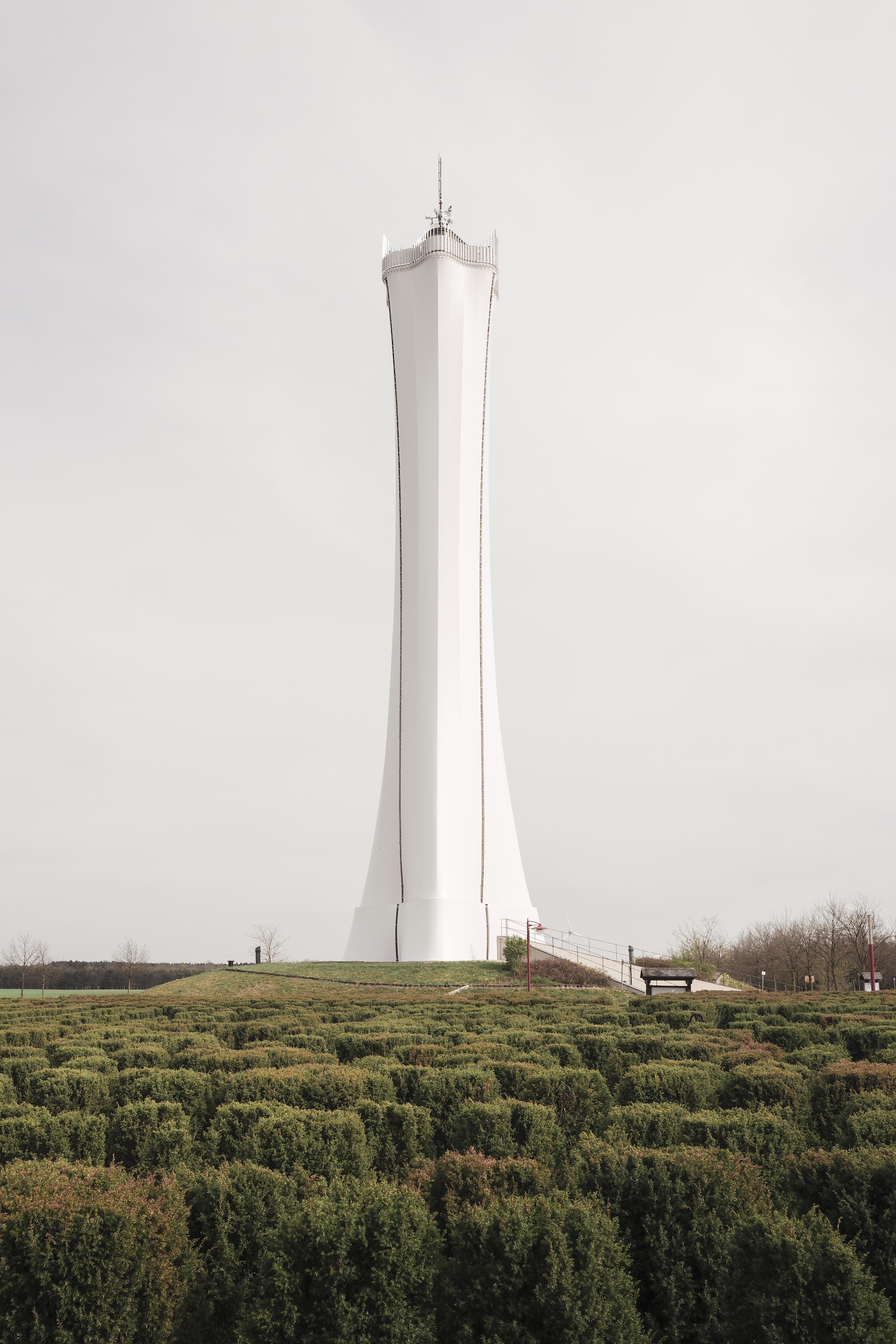 White tower on a grassy hill behind a hedge maze in the Lusatian lignite mining region