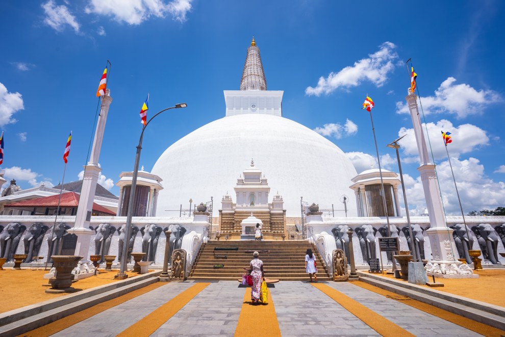 White Ruwanwelisaya stupa beneath a blue sky with pilgrims on the forecourt in Anuradhapura, Sri Lanka