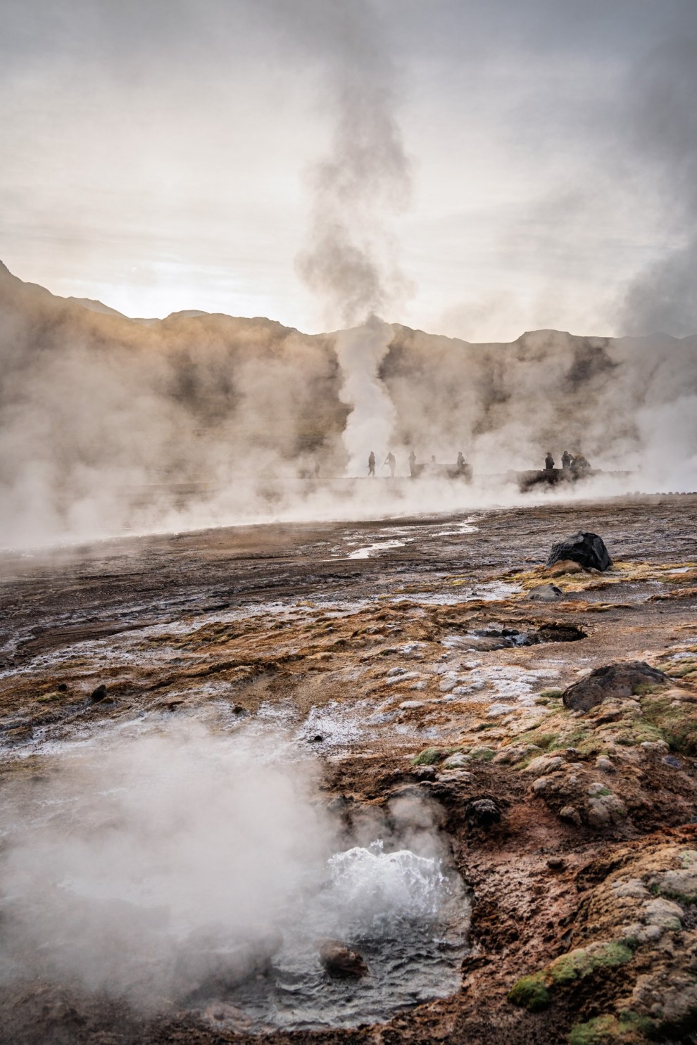 Steam rising from the geysers of El Tatio with small figures in the distance, Chile