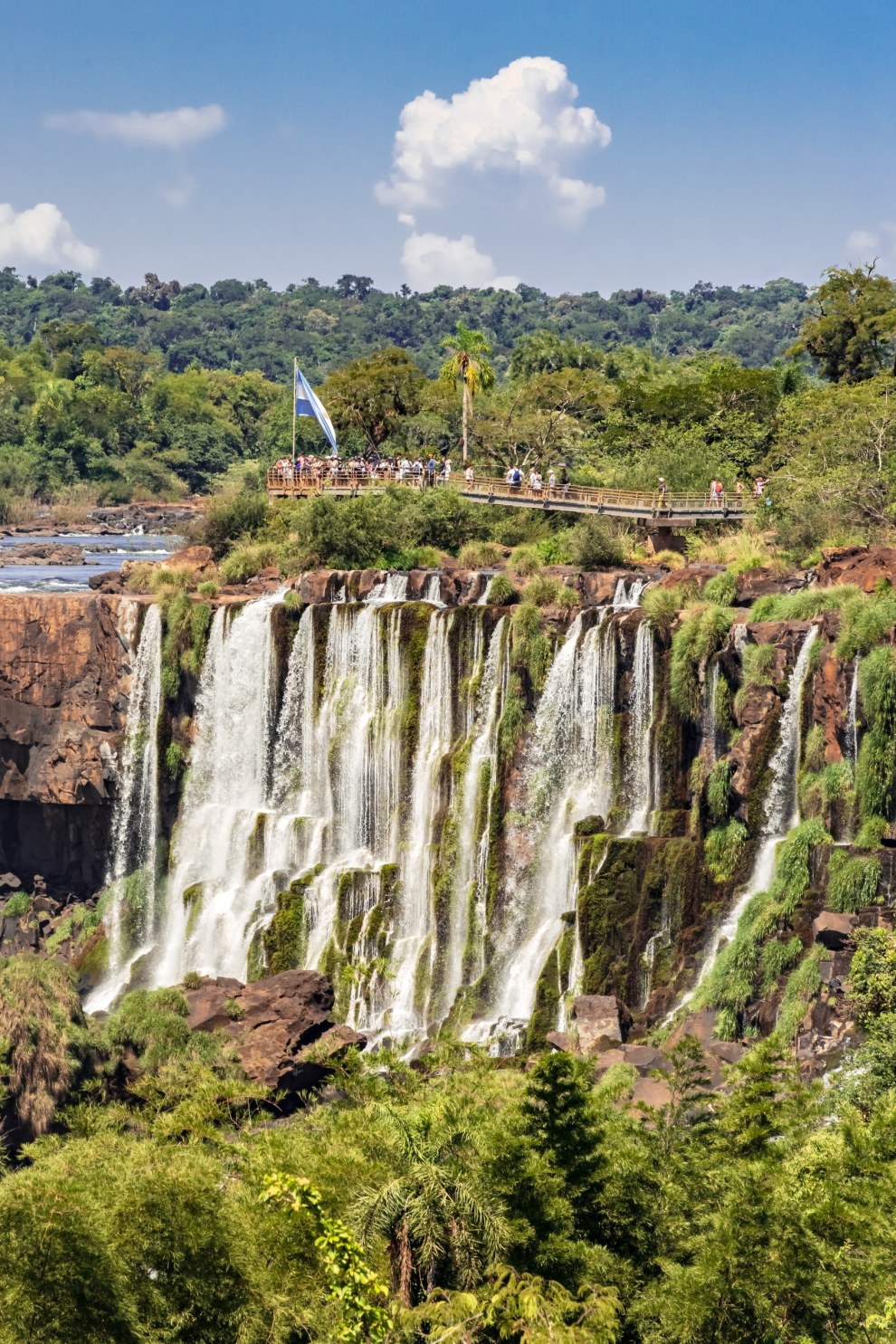 Waterfalls cascading over a cliff surrounded by rainforest at Iguazú Falls, Argentina