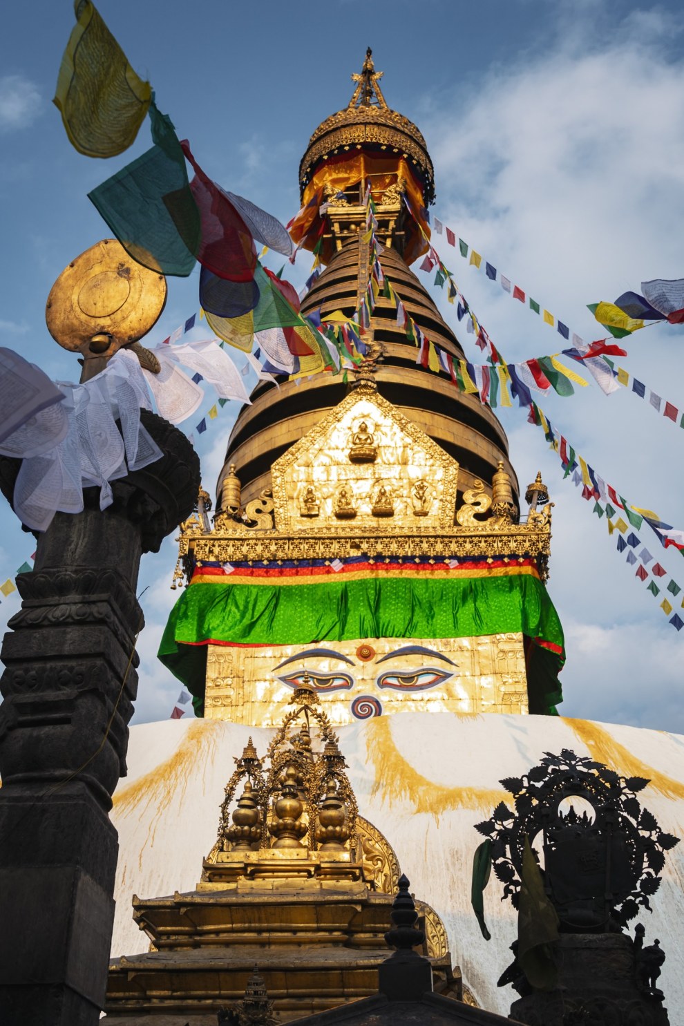 Golden spire and painted Buddha eyes of the Swayambhunath stupa with prayer flags, Kathmandu, Nepal