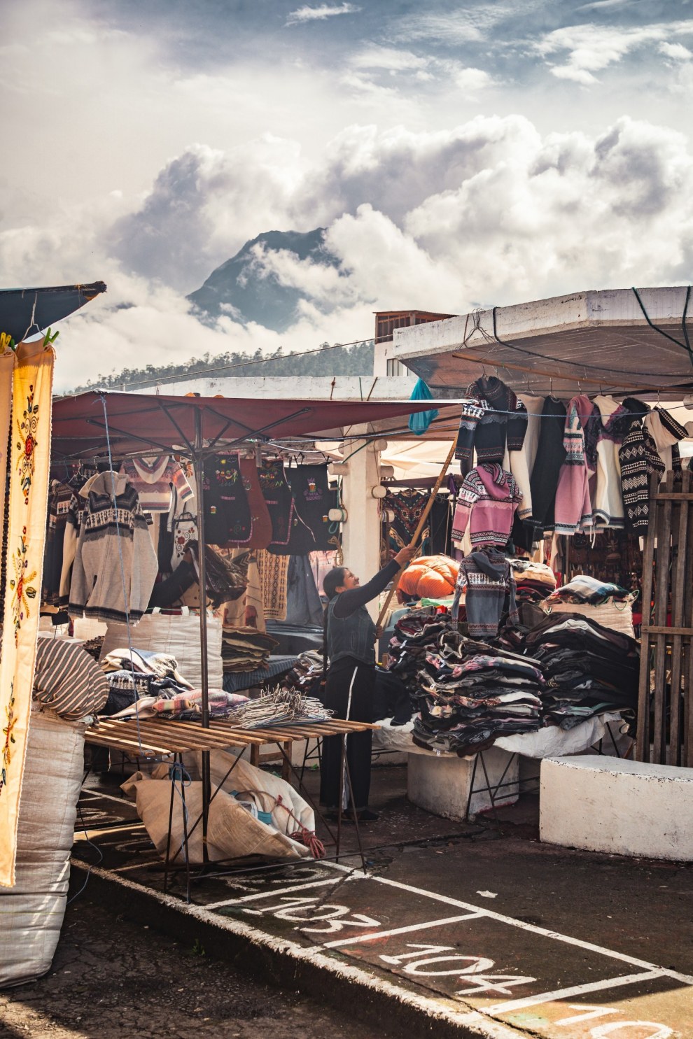 Market stall with clothing in front of a cloud-wrapped volcano in Otavalo, Ecuador
