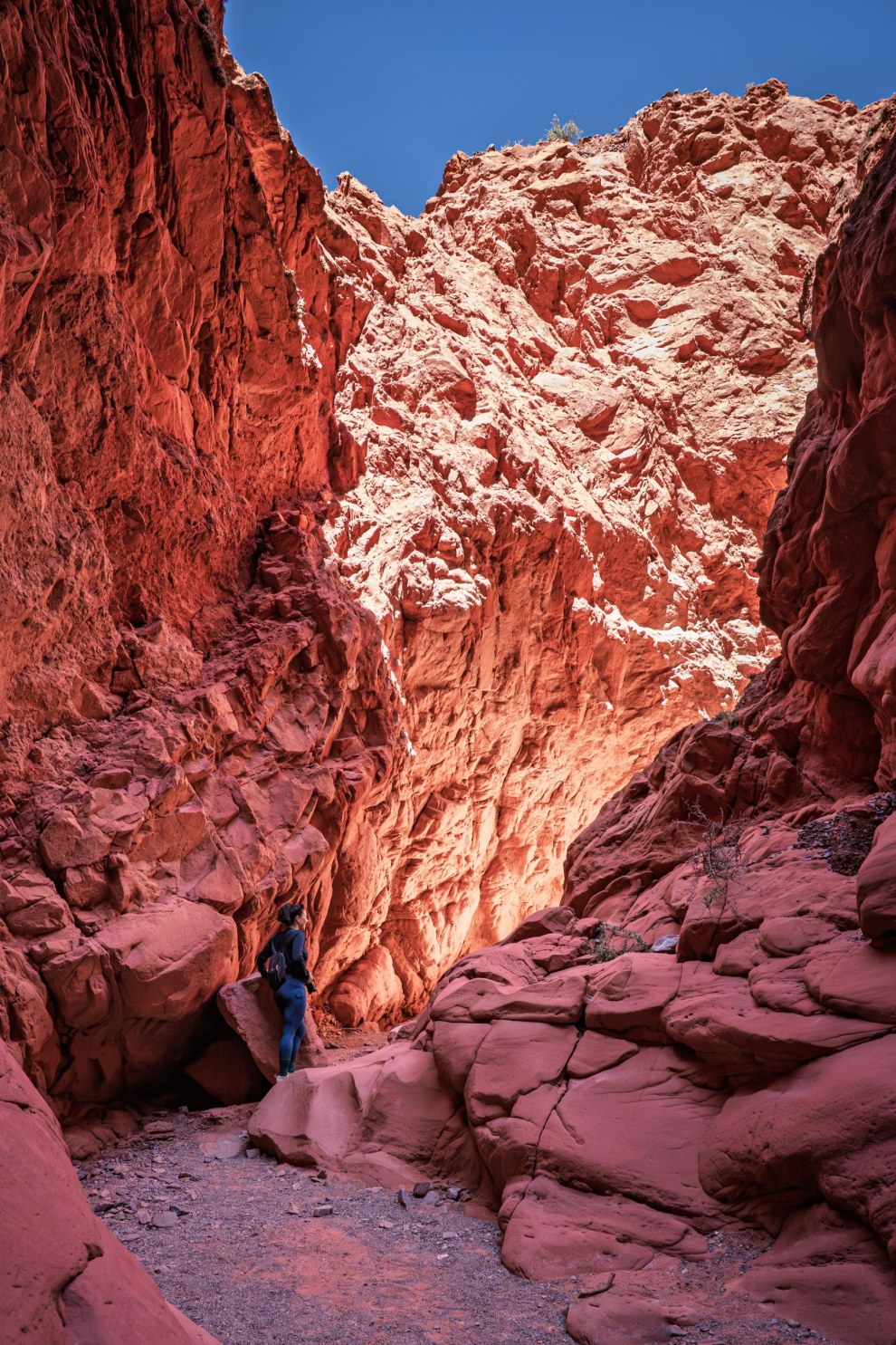 Small figure standing between towering red rock walls in the Quebrada de las Señoritas, Argentina