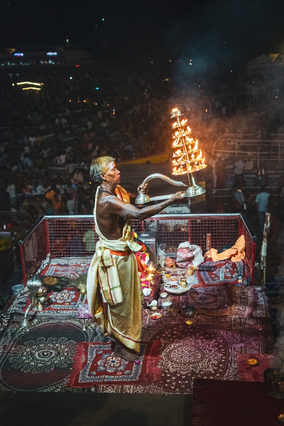 Priest raising a multi-tiered fire lamp during the evening aarti ceremony in Varanasi, India