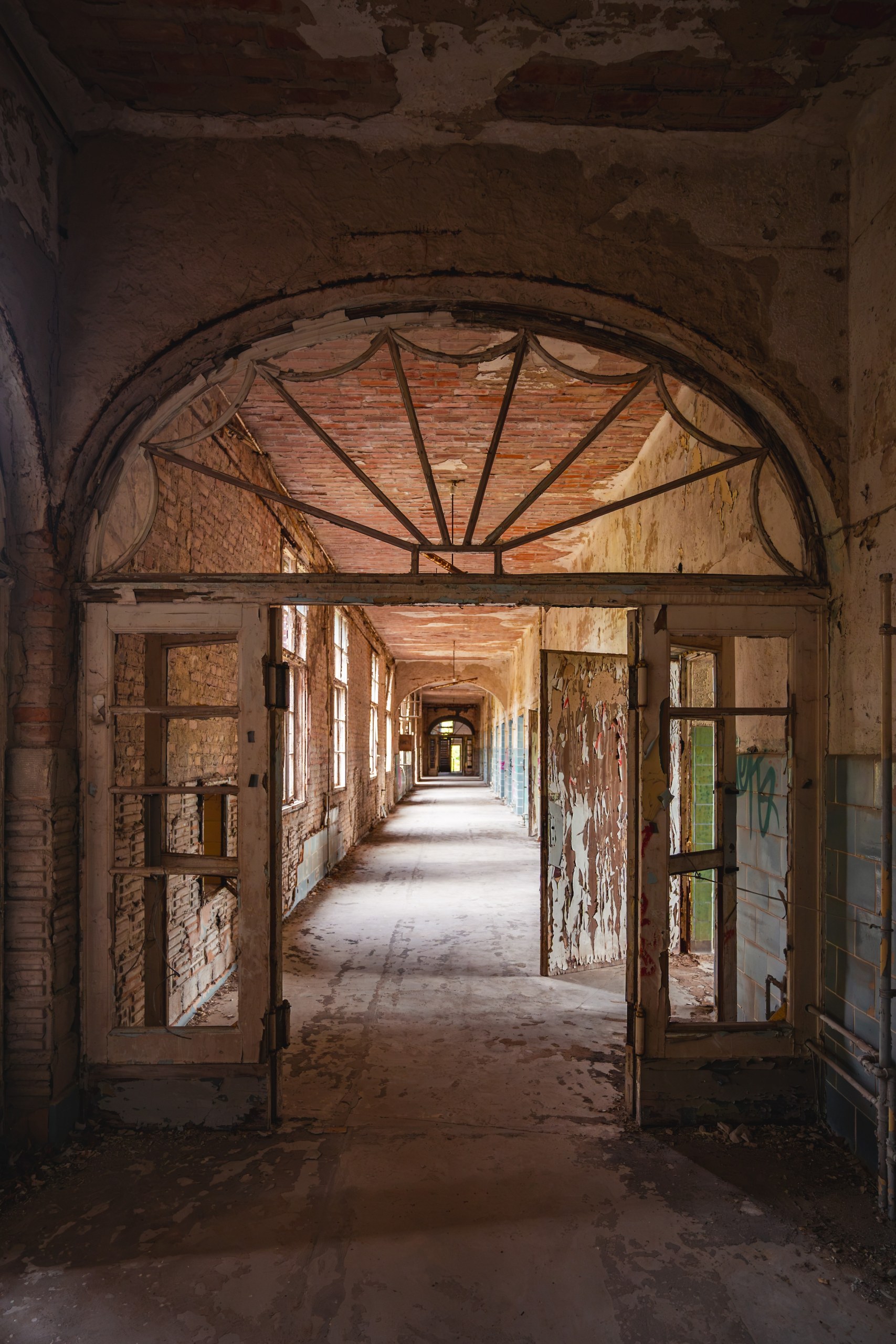 Long arched corridor with peeling paint in an abandoned sanatorium, Beelitz, Germany