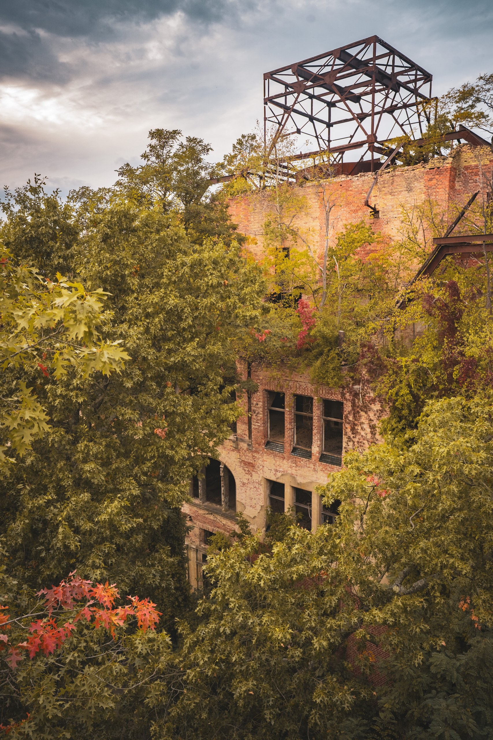 Ruined building with an iron frame on its roof, surrounded by autumn trees, Beelitz, Germany