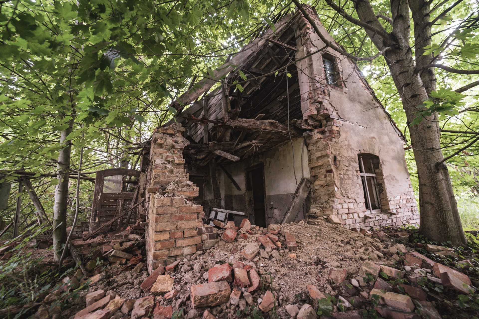 Collapsed brick house in a forest, its walls crumbling into a pile of rubble, Cottbus, Germany
