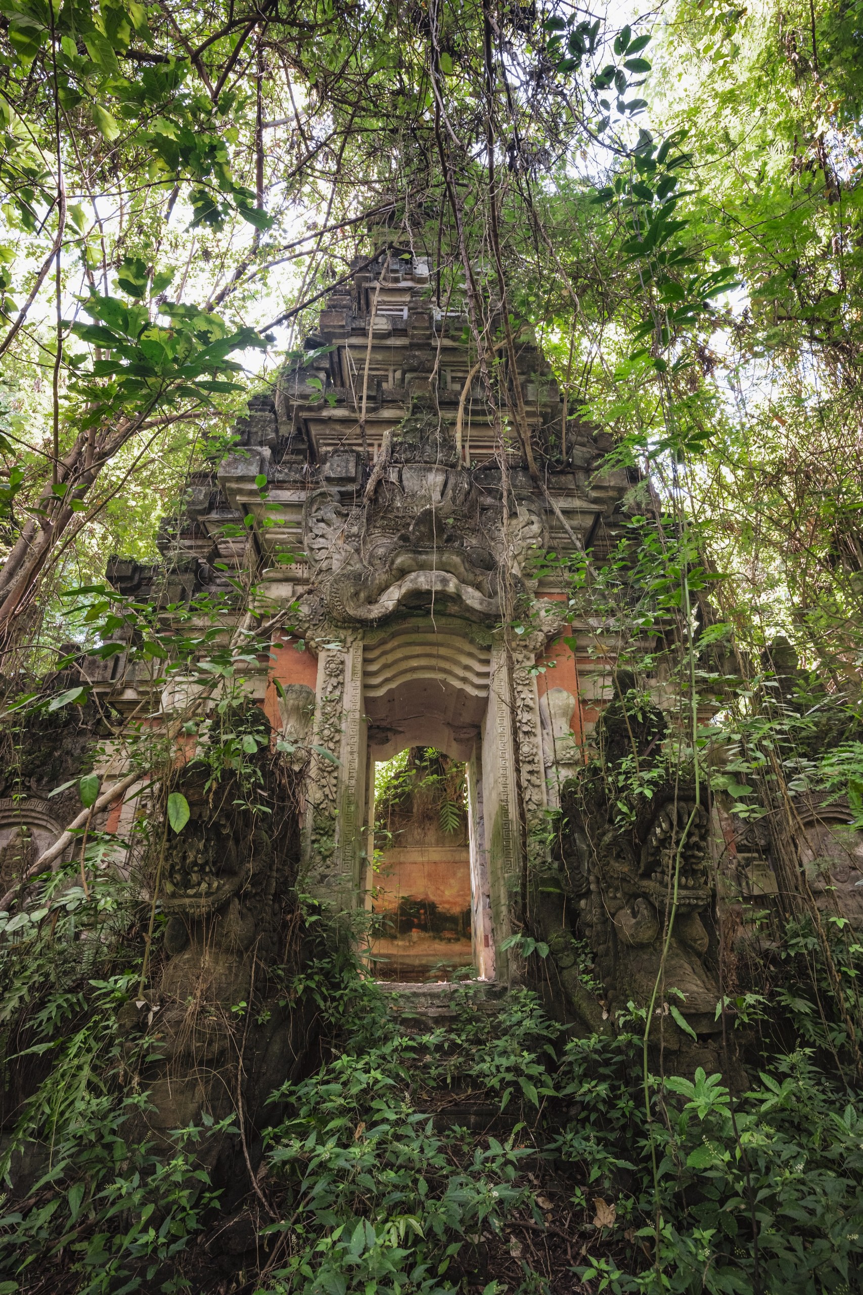 Ornate temple gate overgrown by jungle vines and plants, Taman Festival, Bali, Indonesia