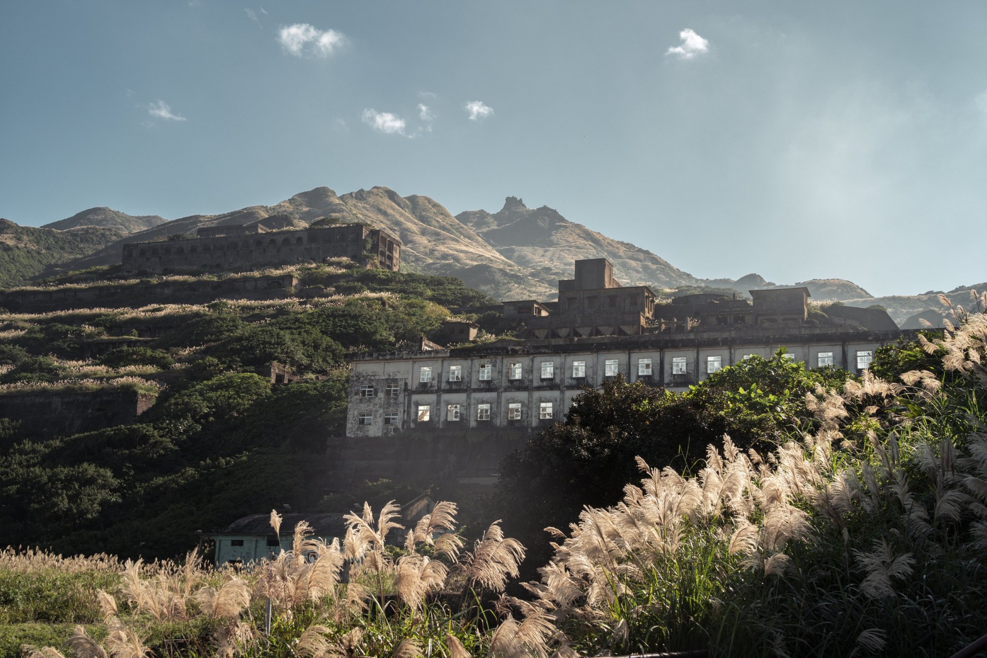 Ruins of an abandoned smelter on a mountain slope behind backlit silvergrass, Ruifang, Taiwan