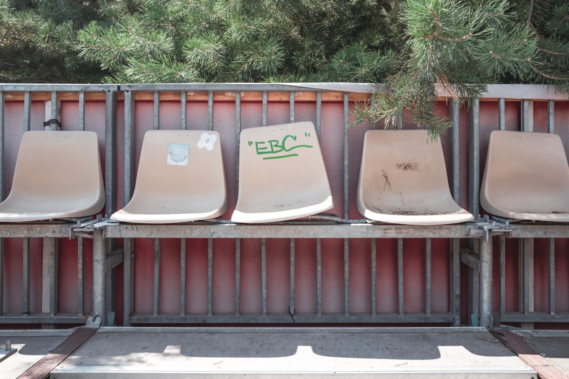 Empty row of plastic seats with graffiti in front of a red container at the deserted Melt! festival site, Ferropolis, Gräfenhainichen, Germany, summer 2020