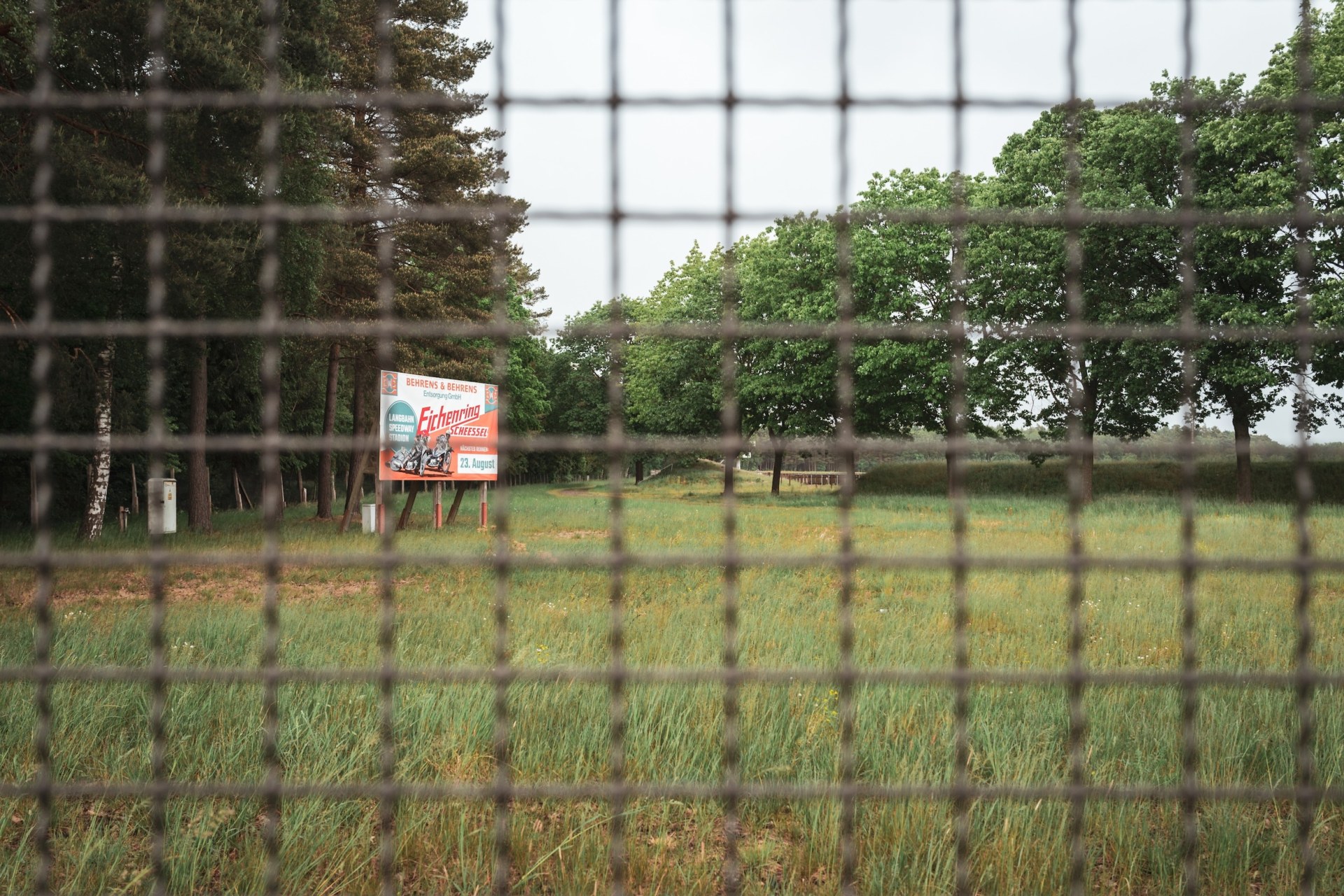 View through a wire fence onto an empty festival meadow, Eichenring, Scheeßel, Germany, summer 2020