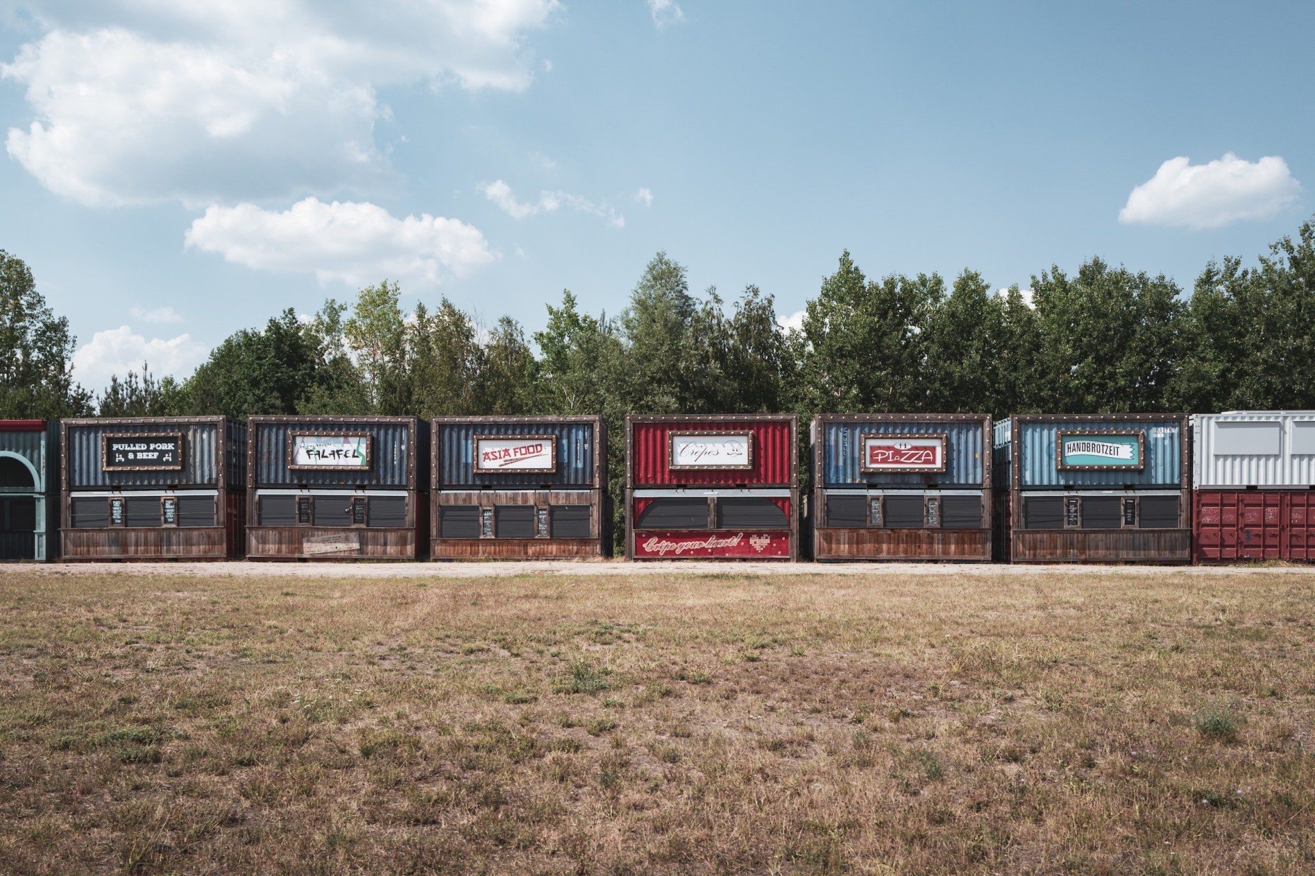 Row of colourful food stall containers on the empty Melt! festival field, Ferropolis, Gräfenhainichen, Germany, summer 2020